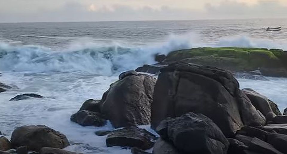 Waves breaking over dark rocks on the shore